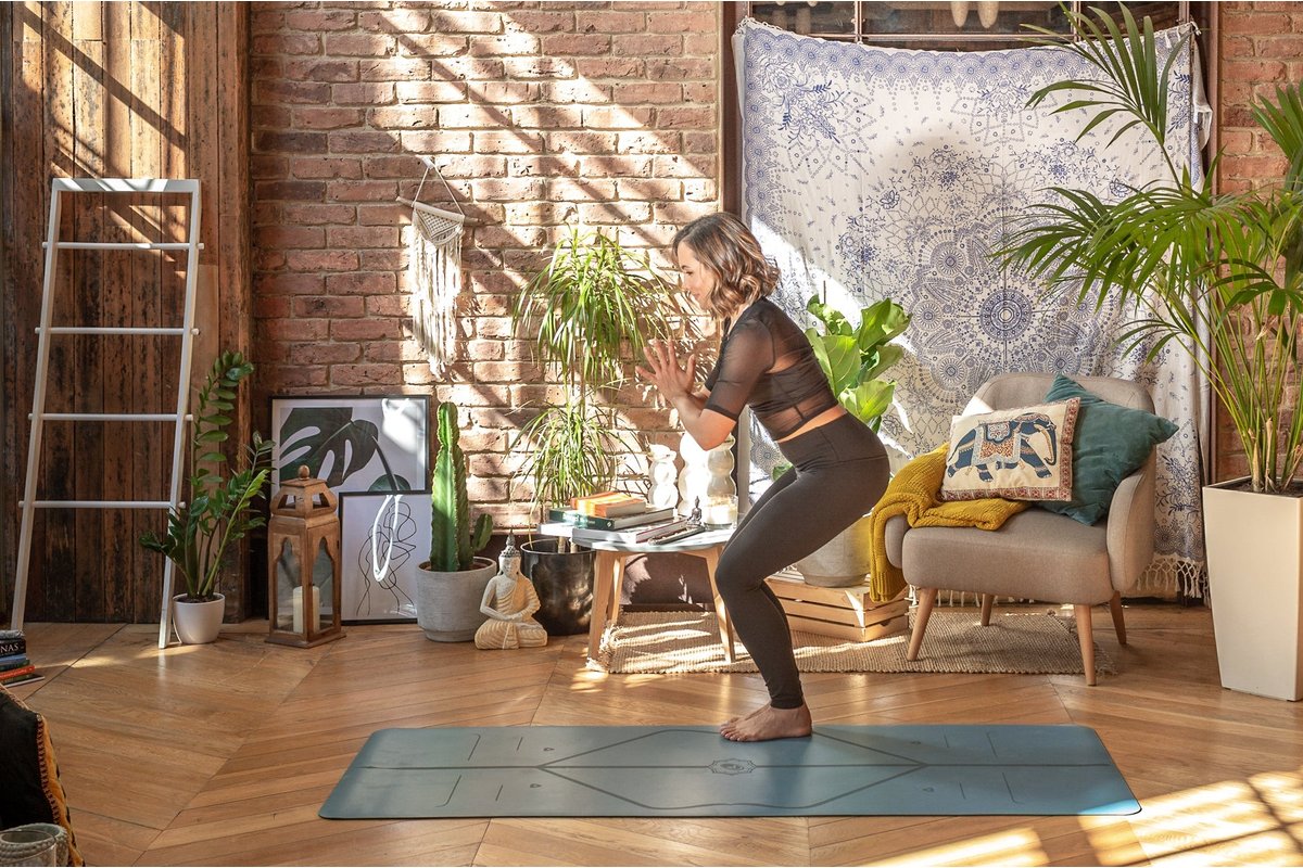 Donna che pratica la posizione del cane a testa in giù su un tappetino yoga.