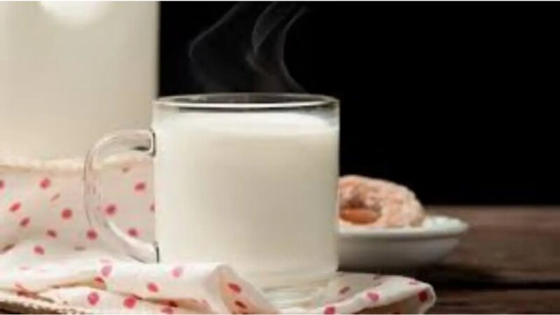 Una tazza di latte caldo su un comodino accanto a un letto.
