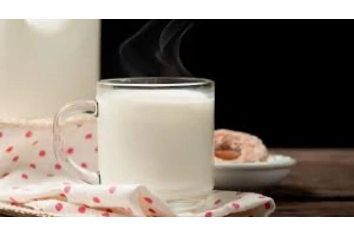 Una tazza di latte caldo su un comodino accanto a un letto.