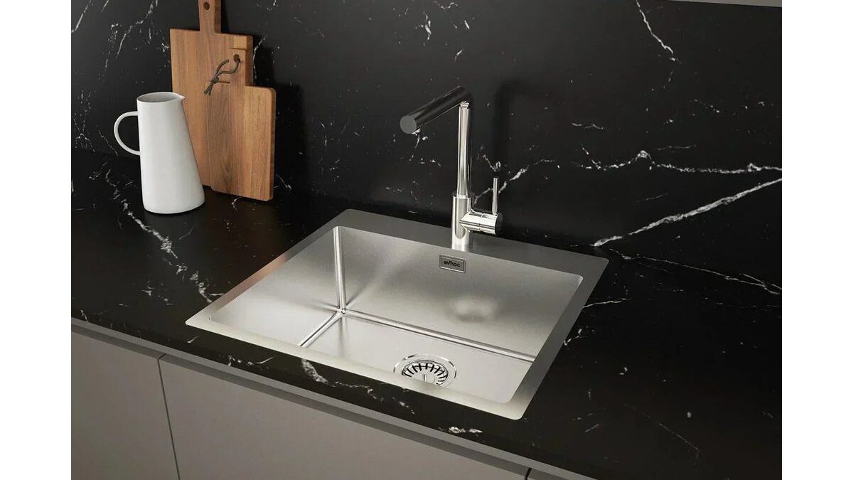 Limone tagliato a metà accanto a un lavello in acciaio lucido.