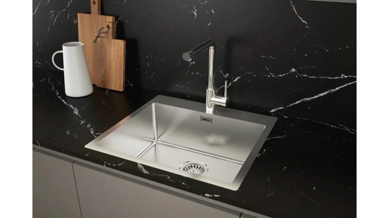 Limone tagliato a metà accanto a un lavello in acciaio lucido.