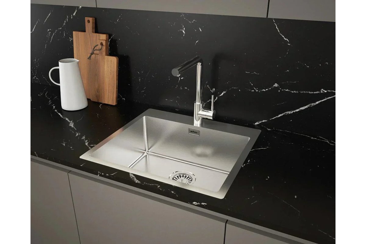 Limone tagliato a metà accanto a un lavello in acciaio lucido.