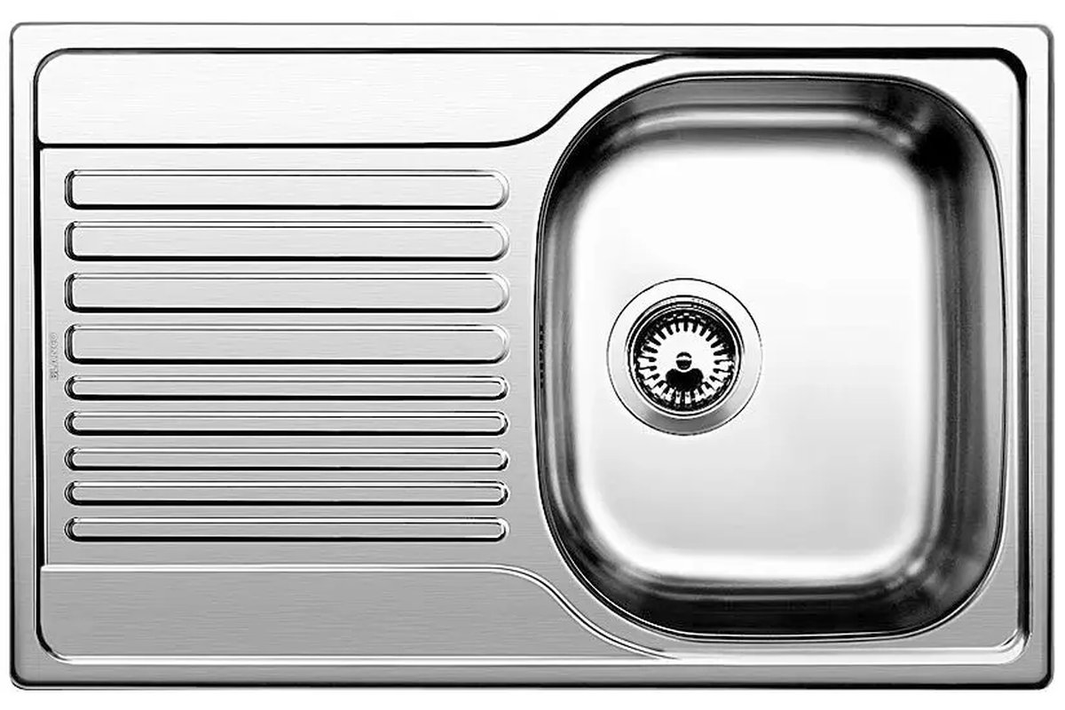 Limone tagliato a metà accanto a un lavello in acciaio lucido.