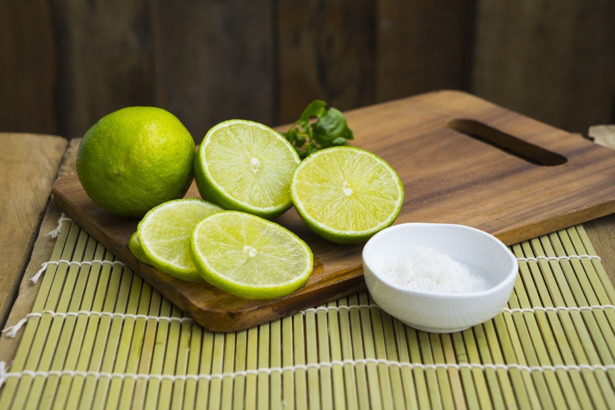 Tagliere in legno con limone tagliato a metà sopra.