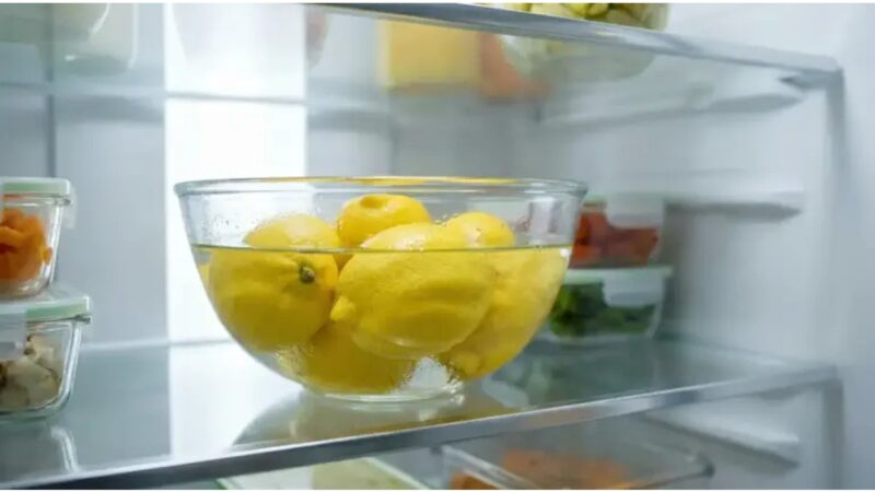 Mezzo limone su un ripiano del frigorifero accanto a vari alimenti.