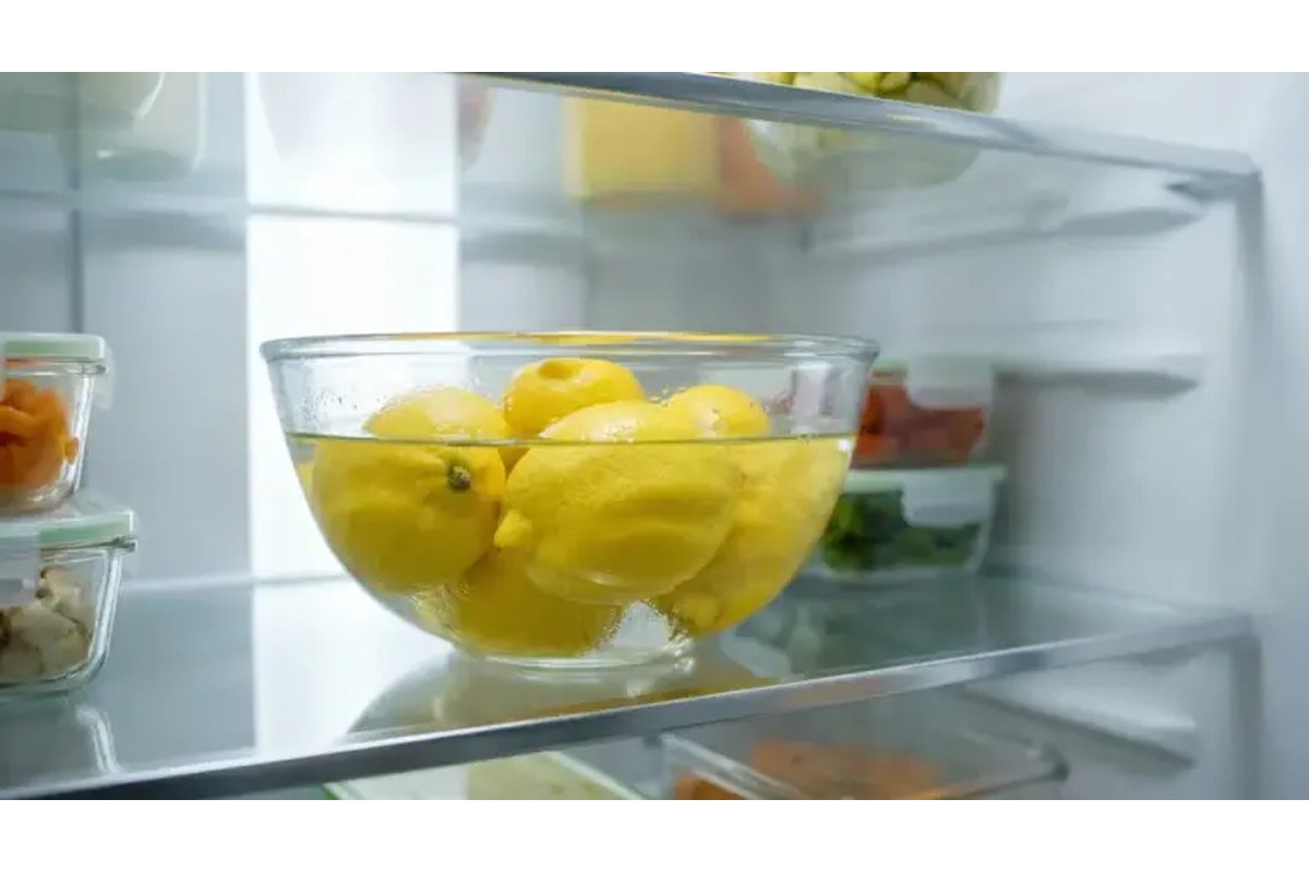 Mezzo limone su un ripiano del frigorifero accanto a vari alimenti.